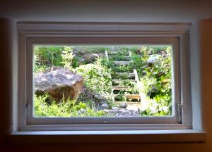 Blick auf den Garten durch ein Fenster in der Unterkunft Apartment with Terrace in the Swedish High Coast in Docksta