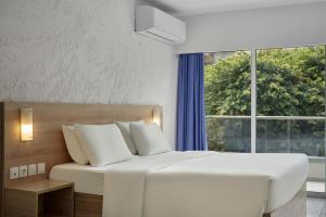 een slaapkamer met een groot wit bed en een raam bij The Apartments by Esperia in Rhodos-stad