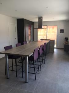 uma sala de jantar com uma grande mesa de madeira e cadeiras roxas em Chambres 24h du Mans em Mulsanne