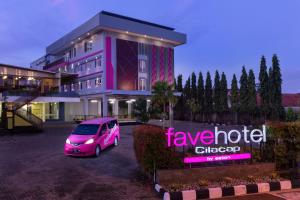 un furgone rosa parcheggiato di fronte a un edificio di favehotel Cilacap a Cilacap