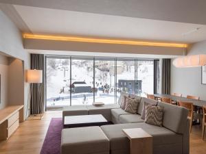 a living room with a couch and a large window at Aya Niseko in Niseko