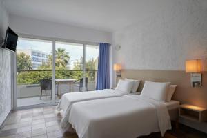 een hotelkamer met 2 bedden en een groot raam bij The Apartments by Esperia in Rhodos-stad