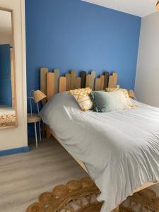 1 dormitorio con 1 cama grande y pared azul en Bel Apt neuf - HyperCentre 400m Plage-Pkg-Wifi-T3, en Arcachon