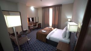 une chambre d'hôtel avec un lit et une chaise dans l'établissement Banoj Hotel, à Erbil