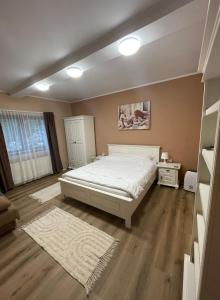 Un dormitorio con una gran cama blanca y suelos de madera. en Studio Sunrise, en Sinaia