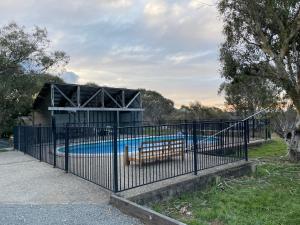 a black fence with a swimming pool behind it at Winterwood Lodge - 6mins Jindabyne -Pets Allow-Floor Heating Winter-Swimming Pool Summer in Moonbah