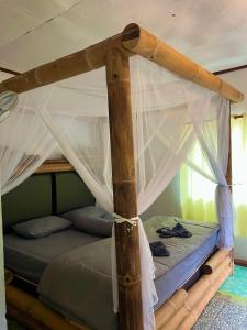 a wooden bed with a canopy in a room at Garden Grove Guest House & Coffee Bar in Bukit Lawang