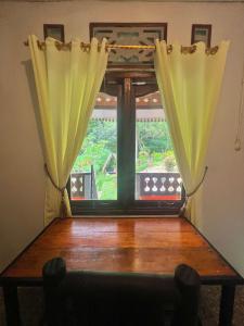 a table with a window with yellow curtains at Garden Grove Guest House & Coffee Bar in Bukit Lawang