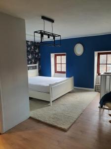 ein Schlafzimmer mit blauen Wänden und einem weißen Bett in der Unterkunft Irie Vibes in Bourganeuf