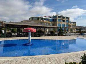 a pool with a red umbrella in front of a building at Aysberq Resort in Baku