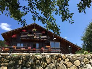 a log house with flowers on the balcony at Le chalet de Doucy Bardet in Habère-Poche