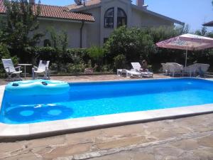 a blue swimming pool with chairs and an umbrella at Family Hotel California - Varna in Varna City