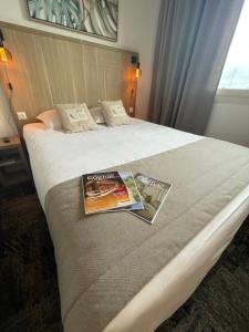 a hotel room with two magazines on a bed at Logis Le Passiflore Cognac in Châteaubernard
