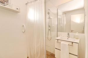 La salle de bains blanche est pourvue d'une douche et d'un lavabo. dans l'établissement Casa Brisa do Mar, à Caldas da Rainha