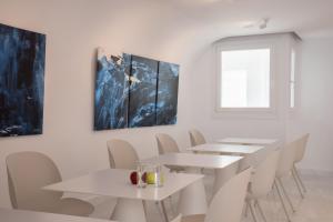 un comedor con mesas blancas y sillas blancas en Petasos Chic Hotel en Mykonos