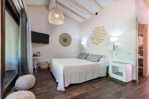 a white bedroom with a bed and two chairs at Hotel Galanias in Bari Sardo