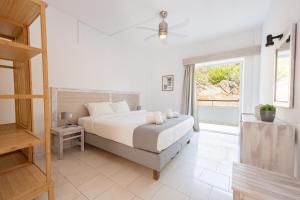 a white bedroom with a bed and a window at Spathies in Kalogria