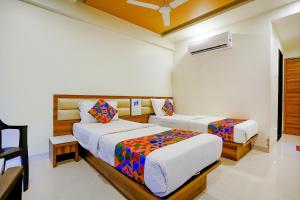 a bedroom with two beds and a chair in it at FabHotel Ramjis Residency in Nashik