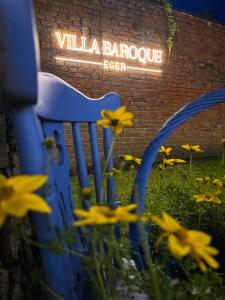 a blue chair sitting in the grass with yellow flowers at Villabaroque_Eger in Eger