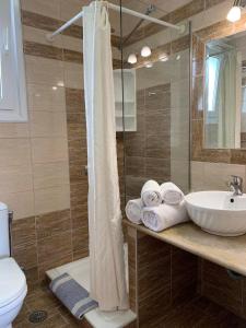 a bathroom with a sink and a shower with towels at Yolanda Studios in Paralia Agias Foteinis