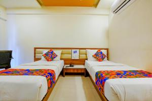 a room with two beds and a table in it at FabHotel Ramjis Residency in Nashik