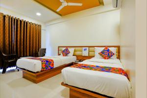 a hotel room with two beds and a window at FabHotel Ramjis Residency in Nashik