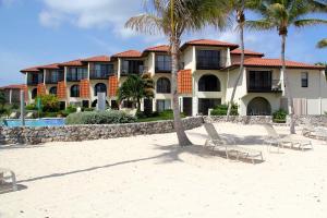 un edificio sulla spiaggia con sedie e palme di Beach Living at Villas Pappagallo (BLPD) a West Bay