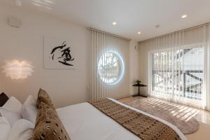 a bedroom with a bed and a large window at Furano Lofts in Furano