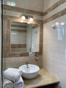 a bathroom with a sink and a mirror and towels at Yolanda Studios in Paralia Agias Foteinis