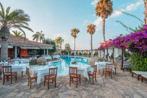 - un restaurant avec des tables et des chaises à côté de la piscine dans l'établissement Hotel Galanias, à Bari Sardo