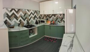 cocina con armarios verdes y nevera blanca en Family house, en Tashkent