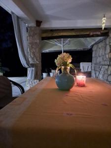un jarrón con flores sentado en una mesa con una vela en TEODORA - kamenný domek 300 m od moře, en Novalja
