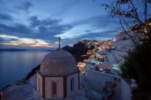 a church with a cross on the side of a city at Amphitheater Cave Houses in Fira