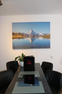 einen Tisch mit Stühlen und ein Bild eines Sees in der Unterkunft Le Vieux Valais in Ovronnaz