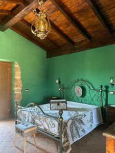 Habitación verde con cama de metal y lámpara de araña. en Agriturismo Le Faeta en Arpino