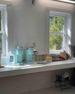 a kitchen counter with two windows and a counter top with food at The Four Pillars Farmstead 