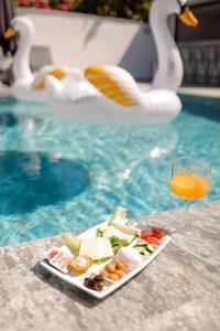 a plate of food and a drink next to a swimming pool at Swan Boutique Hotel in Bodrum City