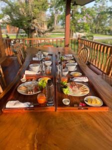 una mesa de madera con platos de comida. en เพลินนะเพลินนารีสอร์ท en Ban Rim Lao