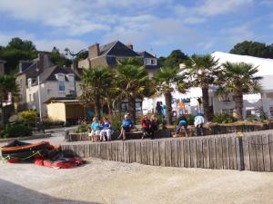 un gruppo di persone seduti su un muro vicino alla spiaggia di studio Marie a Cancale