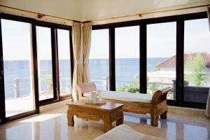 Zimmer mit einem Bett, einem Tisch und Fenstern in der Unterkunft Alam Bali Beach Resort in Amed