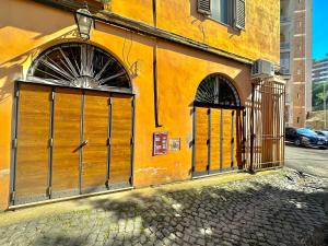 an orange building with two gates on a street at Trastevere Loft in Rome