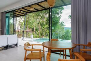 una sala da pranzo con tavolo, sedie e piscina di HinKong View Pool Villa Koh Phangan a Hinkong