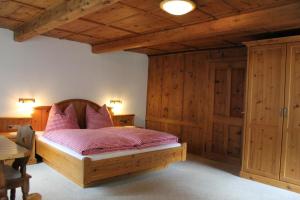 a bedroom with a wooden bed with pink pillows at Haus Eder in Ginzling