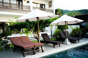 a group of chairs and umbrellas next to a pool at Alam Bali Beach Resort in Amed