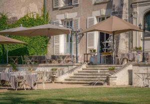 un patio avec des tables et des parasols en face d'un bâtiment dans l'établissement Château De Pray, à Amboise