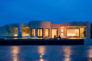 dos personas sentadas frente a una casa por la noche en Senses Luxury Houses, en Fira