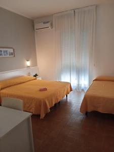 a hotel room with two beds and a window at Hotel Haiti in Milano Marittima