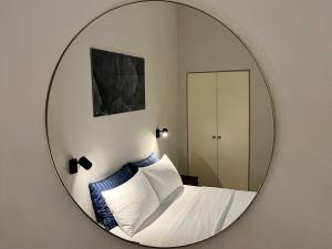 specchio che riflette una camera da letto con letto e cuscini. di Arno Boutique a Firenze