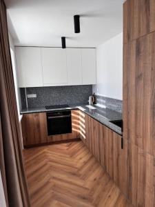 a kitchen with white cabinets and a wooden floor at Apartment in the old town in Kėdainiai
