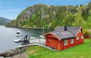 a red house on a dock with a boat in the water at Stunning Home In Mosvik With House Sea View in Mosvik